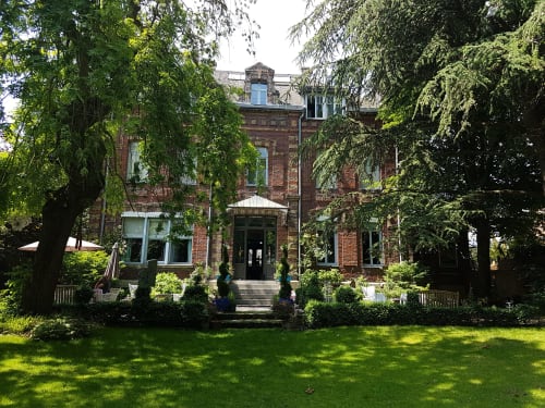 Le Grand Duc B&B à Valenciennes : demeure en brique entourée de verdure luxuriante et pelouse soignée