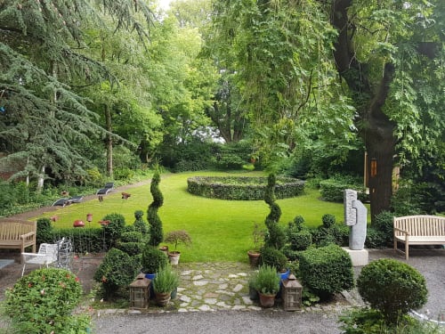 Le jardin du Grand Duc à Valenciennes avec pelouse impeccable, topiaires, bancs et arbres majestueux