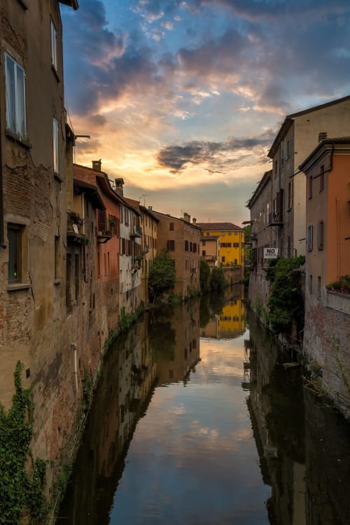 Sereno canale a Borgo Virgilio, Mantova con edifici storici colorati riflessi nell'acqua al tramonto