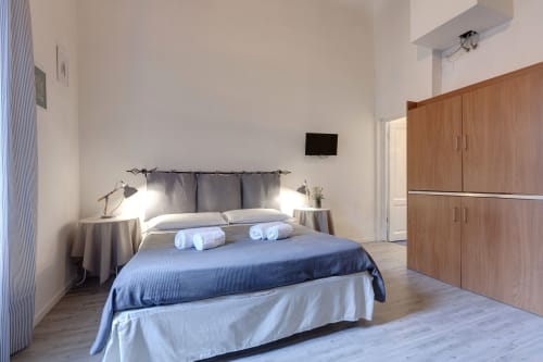 Modern studio bedroom at Sleep tight Florence with blue bedding, wooden wardrobe, and minimalist decor in Firenze