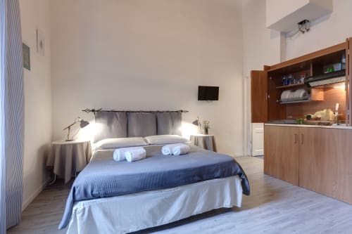Sleep tight Florence studio apartment in Firenze with blue bedding, wooden kitchenette, TV, and modern amenities