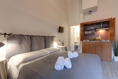 Bright studio apartment at Sleep tight Florence with bed, rolled towels, wooden kitchenette, and modern amenities in Firenze