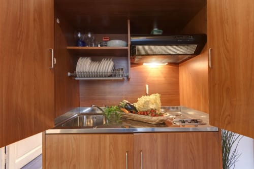 Modern compact kitchen in Florence apartment with wooden cabinets, stainless steel countertop, and fresh ingredients
