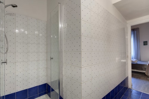 Modern bathroom shower enclosure at Sleep tight Florence with white tiled walls, blue accents, and glass doors