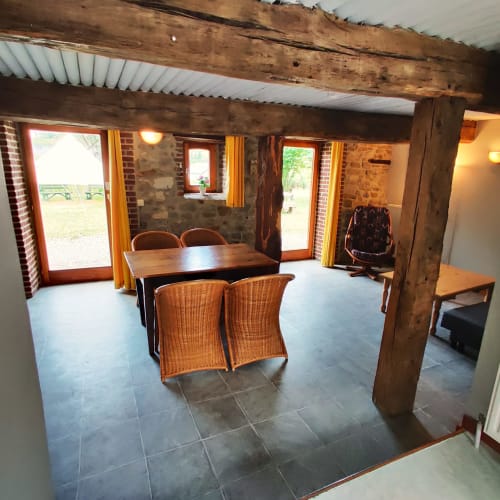Spacieux appartement au rez-de-chaussée à La Ferme De Werpin, zone de repas, fauteuils en rotin, poutres en bois et accès jardin