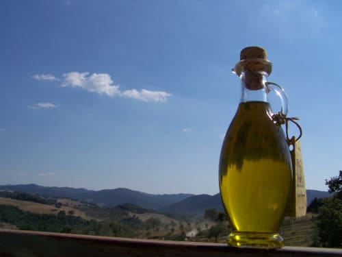 Bottiglia di olio d'oliva con paesaggio della campagna toscana presso Agri-Bio Santa Palmira, Pomarance