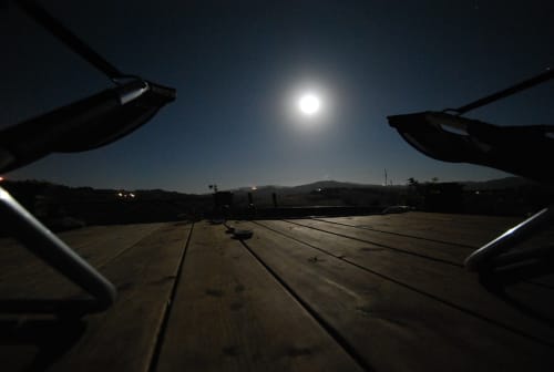 Terrazza in legno illuminata dalla luna presso Agri-Bio Santa Palmira a Pomarance, Italia, con vista sulle montagne e il cielo notturno