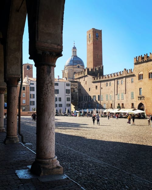 Piazza storica di Mantova con torri medievali e cupola vista attraverso antiche colonne presso B&B Emozioni Relax