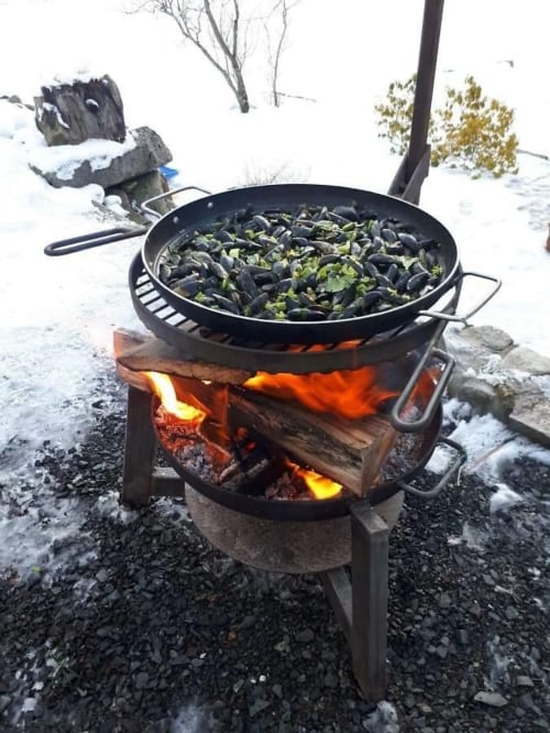 Moules cuisant dans un wok sur feu de bois à Villa Valtin, Le Valtin, repas en plein air enneigé