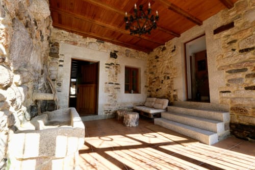Patio interior rústico de piedra en la propiedad rural Balbino en León, España con techo de vigas de madera y estilo tradicional