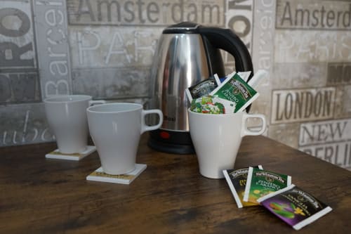 Tea and coffee service setup in Naples hotel room with kettle, mugs, and tea packets on wooden table