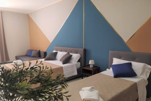 Modern family room at Royal Rooms Station Napoli with twin beds, geometric blue accent wall, and city views in Naples, Italy