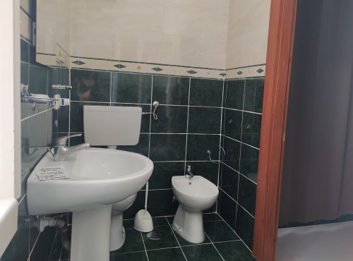 Private bathroom in Family Room at Royal Rooms Station Napoli with sink, toilet, bidet, and green tiled walls