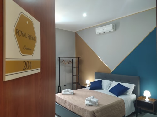 Superior King Room 204 at Royal Rooms Station Napoli with modern blue accent wall, bed with navy pillows, and city views