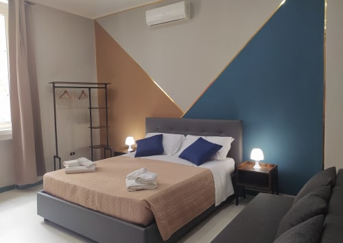 Modern Superior King Room at Royal Rooms Station Napoli with blue and tan accent walls, queen bed, bedside lamps, and