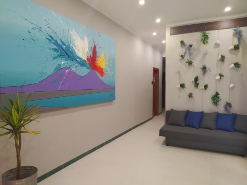 Modern hotel lobby at Royal Rooms Station Napoli featuring colorful volcano artwork and living green wall with gray sofa