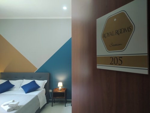 Royal Rooms Station room 205 in Naples with modern double bed, blue accents, and geometric wall design
