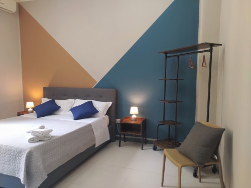 Modern hotel bedroom at Royal Rooms Station Napoli with geometric blue and tan accent wall, double bed with blue pillows, and