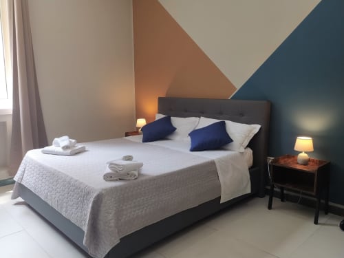 Modern double bedroom at Royal Rooms Station Napoli with geometric wall design, navy pillows, and city view in Naples, Italy