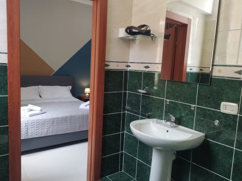 Bathroom with green tiled walls and pedestal sink in large double room at Royal Rooms Station Napoli, Naples