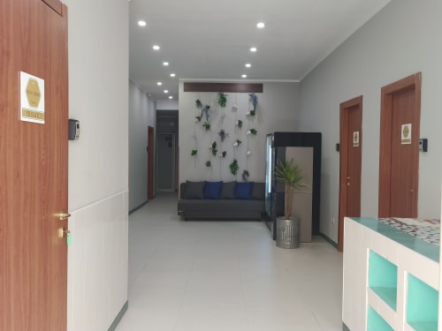 Modern lobby of Royal Rooms Station Napoli in Naples with wooden doors, gray tiled flooring, comfortable seating, and living