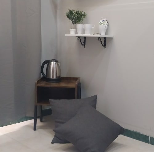Cozy hotel room corner at Royal Rooms Station Napoli with shelf, kettle, and modern decor