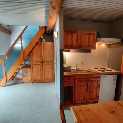 Split-level apartment kitchen at La Ferme De Werpin with wooden cabinets, stove, sink, refrigerator and dining area