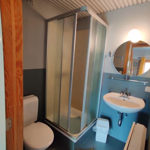 Modern bathroom with blue walls, white sink, round mirror, and glass shower enclosure at La Ferme De Werpin in Hotton
