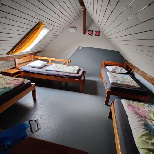 Attic bedroom with four wooden beds and colorful bedding at La Ferme De Werpin in Hotton, Belgium