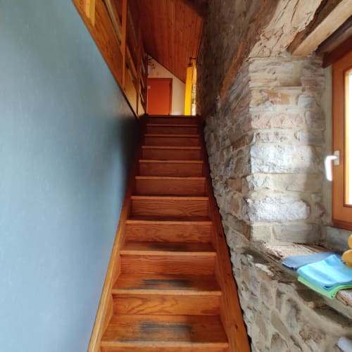 Wooden staircase ascending in narrow hallway with exposed brick wall at La Ferme De Werpin, Belgium