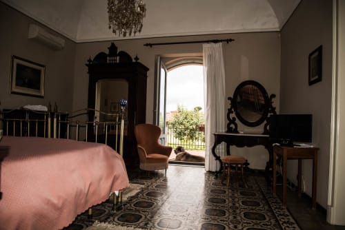 Camera elegante a B&B Valle Allegra a Gravina di Catania con mobili neri ornamentali, biancheria rosa e vista sulle montagne