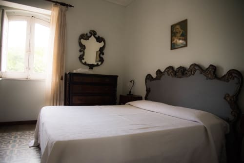 Camera elegante di B&B Valle Allegra con testata decorativa, biancheria bianca e vista sul giardino a Gravina di Catania