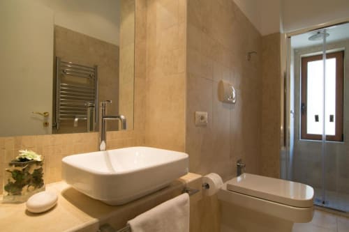 Modern bathroom at Maison Vaticana Guest House Rome with white vessel sink, rainfall shower, and beige tile finishes