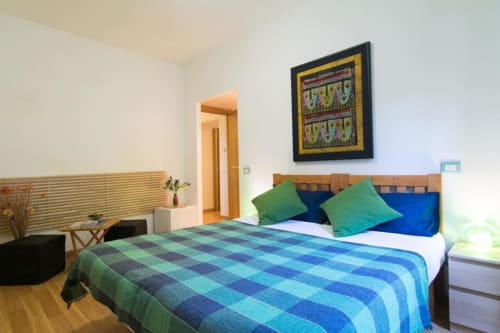 Modern bedroom at Maison Vaticana Guest House Rome with blue checkered bedding, green pillows, wooden bed frame, and