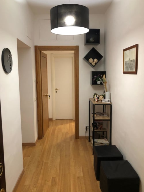 Modern hallway at Maison Vaticana Guest House Rome with wooden doors, black pendant light, and decorative shelving