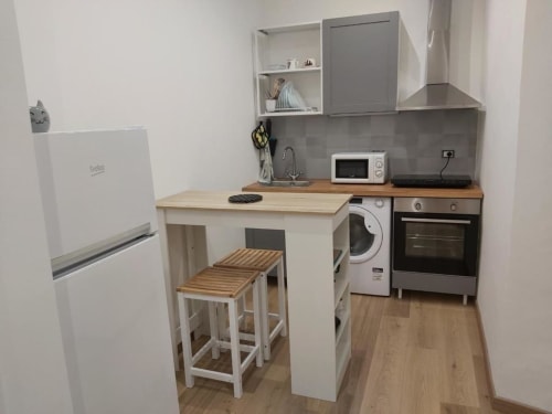 Modern kitchenette at Maison Vaticana Guest House Rome with refrigerator, stove, microwave, and bar seating