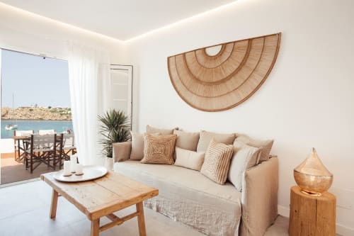 Luminosa sala de estar de apartamento costero con vista al mar, sofá beige, decoración de madera y mobiliario mediterráneo en Las