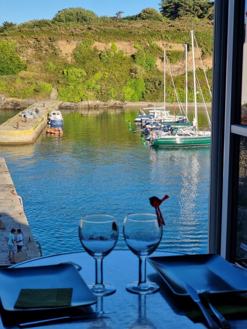 Deux verres de vin sur une table face au port de Locmaria rempli de voiliers, Belle Île en Mer