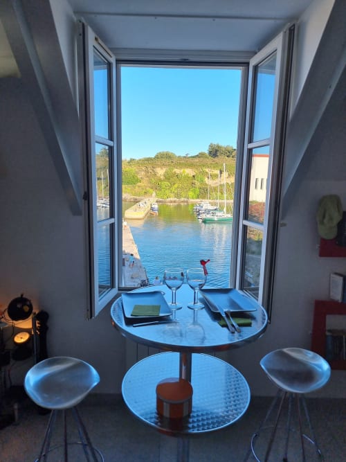 Appartement à Sauzon aux portes ouvertes surplombant le port, table de salle à manger avec verres de vin, Belle-Île-en-Mer