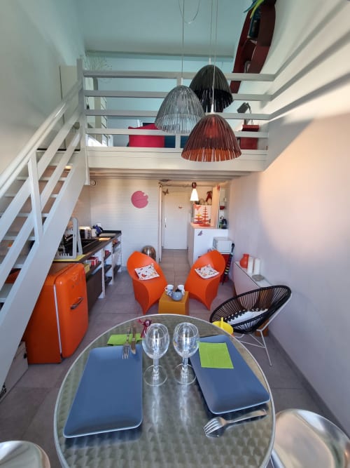 Intérieur moderne de l'appartement Locations Loc'Maria avec assises orangées, coin repas et mezzanine vue mer, Belle-île-en-Mer