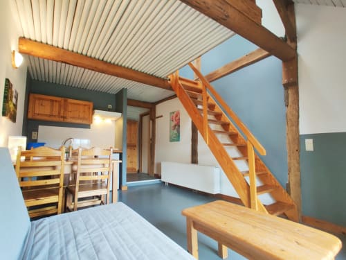 Spacious apartment at La Ferme De Werpin with wooden loft stairs, kitchen area, and garden views in Hotton, Belgium