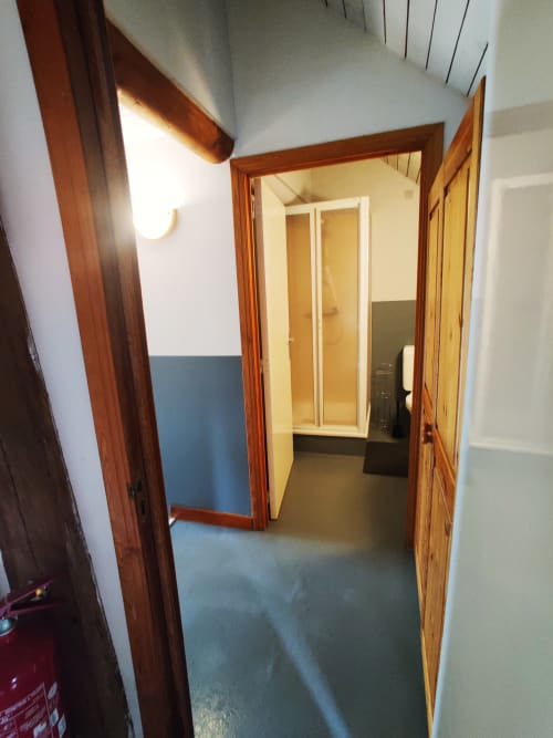 Hallway entrance to apartment at La Ferme De Werpin BnB in Hotton, Belgium, with wooden doors and blue flooring
