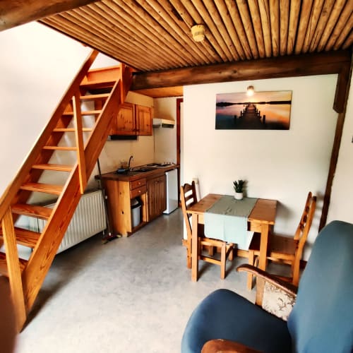 Appartement cosy à La Ferme De Werpin avec escalier de mezzanine en bois, kitchenette, table à manger et coin salon