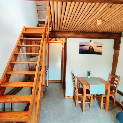 Cozy apartment at La Ferme De Werpin with wooden stairs, dining table, and bedroom loft in Hotton