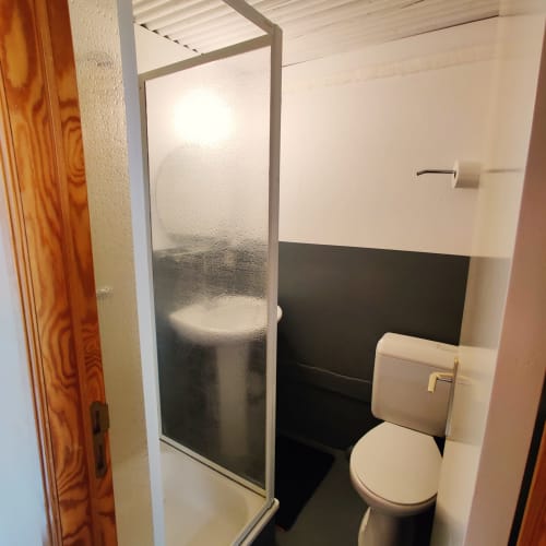 Compact bathroom with toilet, sink, and glass shower enclosure at La Ferme De Werpin BnB apartment