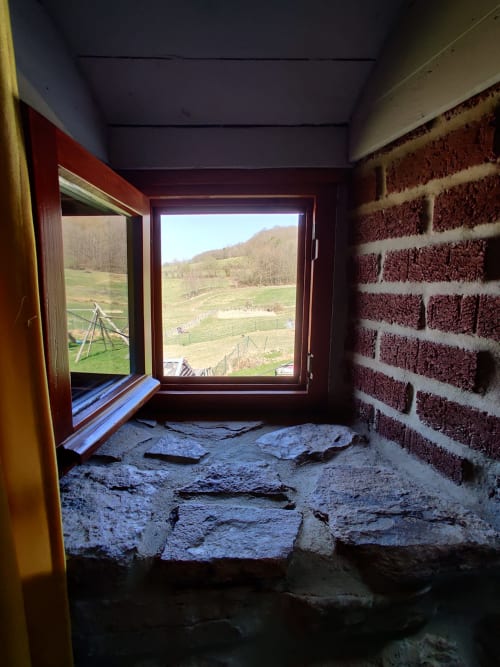 Vue de construction depuis l'appartement de La Ferme De Werpin montrant le paysage rural de la vallée à travers les fenêtres ouvertes