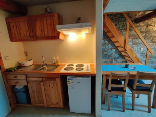 Cuisine compacte et espace repas dans l'appartement avec vue montagne à La Ferme De Werpin, Hotton, avec meubles en bois et plaque électrique