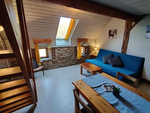 Spacieux appartement avec vue montagne à La Ferme De Werpin, canapé bleu, mobilier en bois, cheminée et puits de lumière à Hotton,