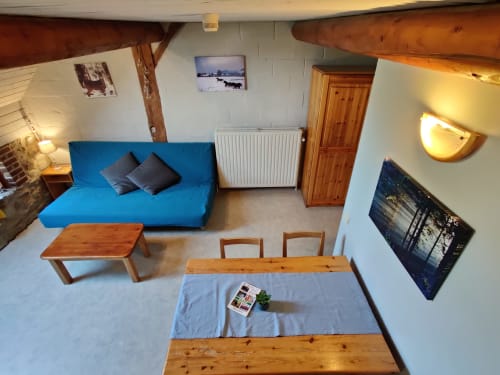 Séjour confortable à La Ferme De Werpin avec canapé bleu, table à manger en bois et espace chauffé
