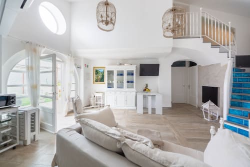 Loft open-plan moderno a Villa Costanza sulla Costiera Amalfitana con divano beige, boiserie bianca, scala blu e lucernari